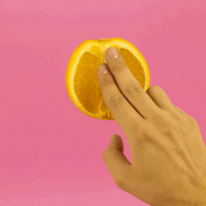 Mano tocando la mitad de una naranja
